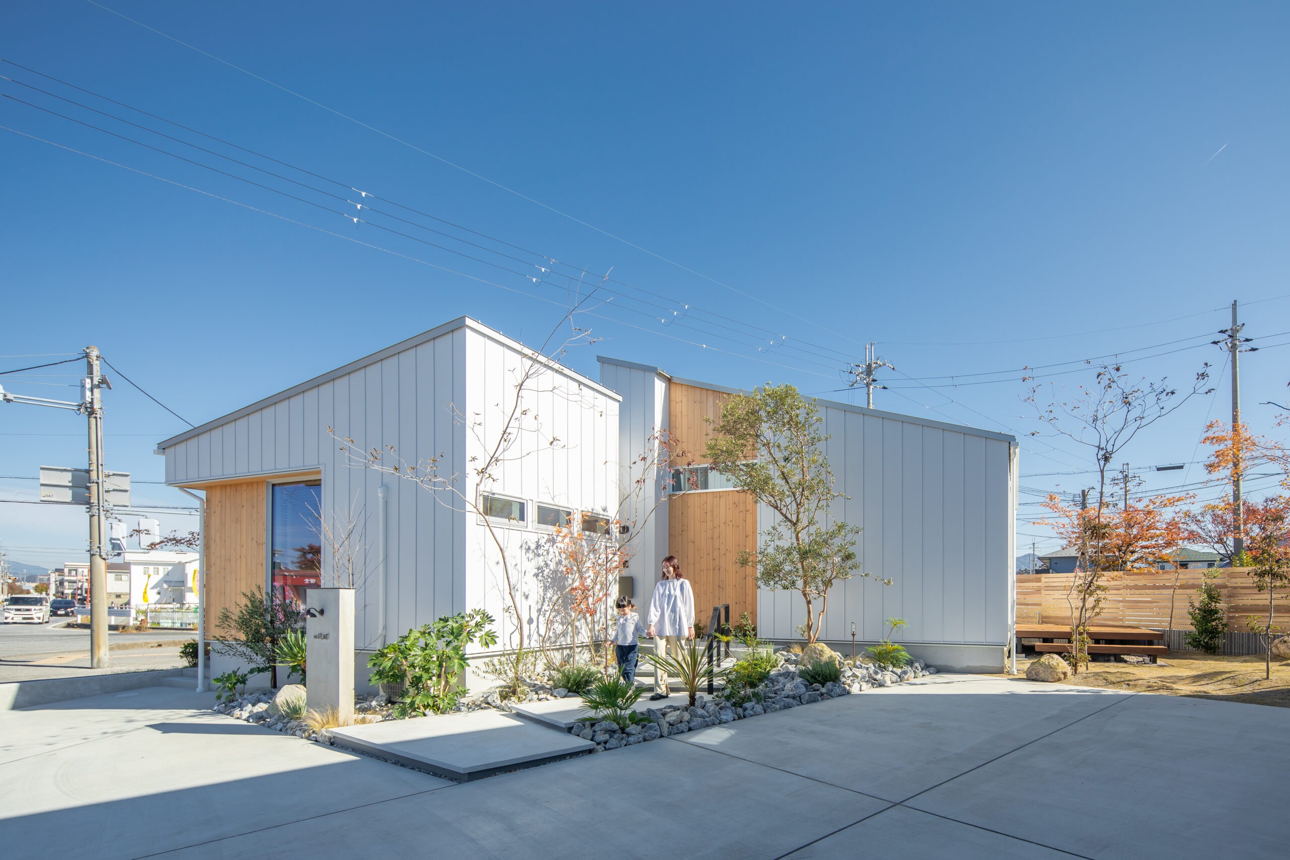 玄関アプローチを歩く家族と滋賀の平屋住宅の外観